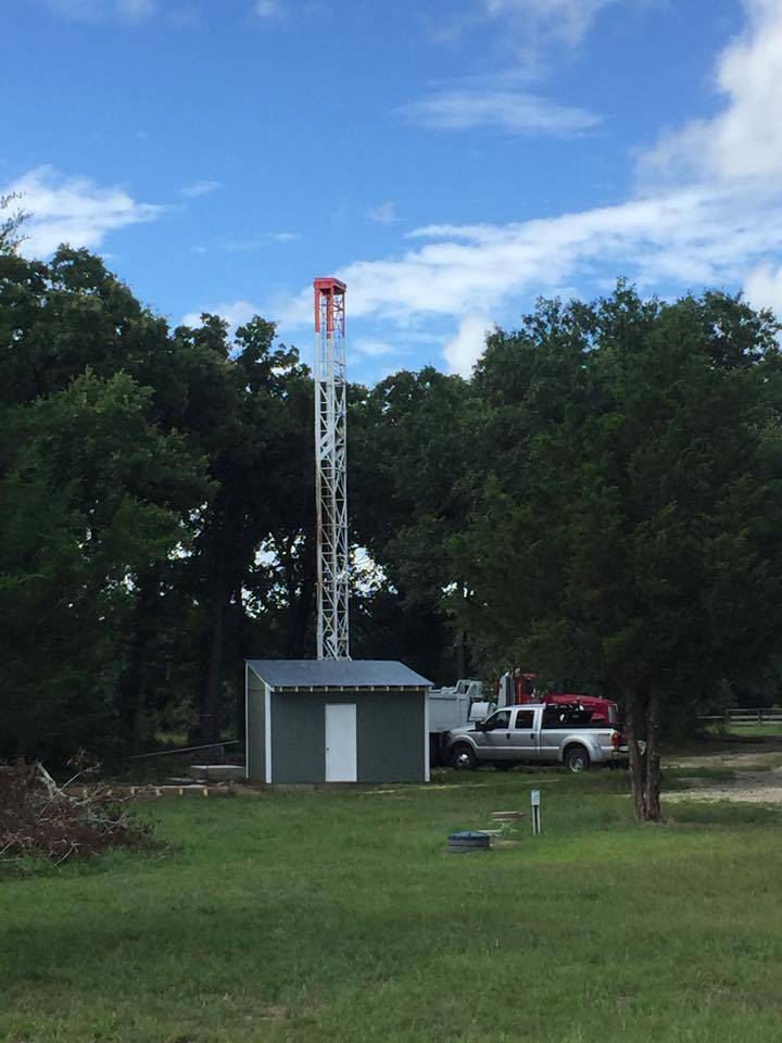 Holly Water Wells rig at a completed well house during a pump installation job