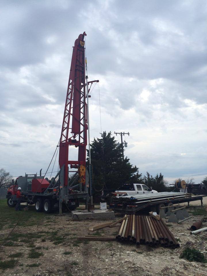 Holly Water Wells service truck and rig staged with well parts and components on-site